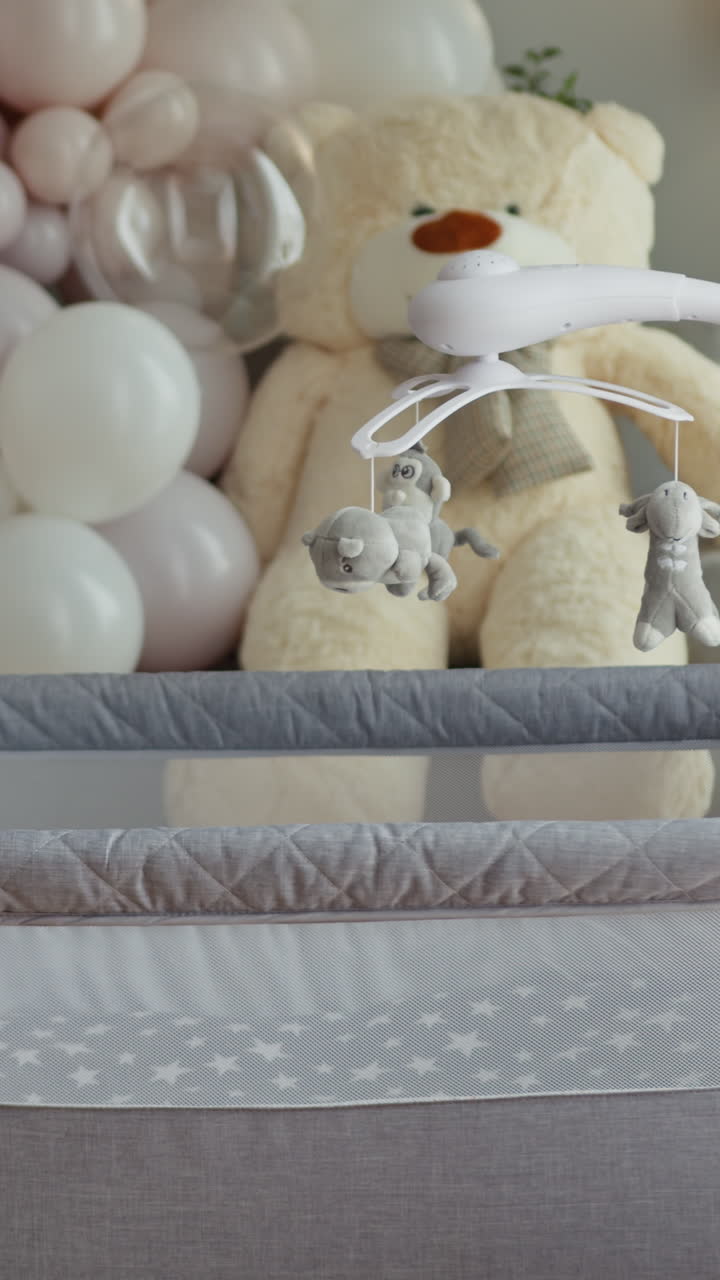 Morbido orsetto di peluche e giocattoli pendenti su una giostrina da culla creano una dolce atmosfera da cameretta con colori pastello.