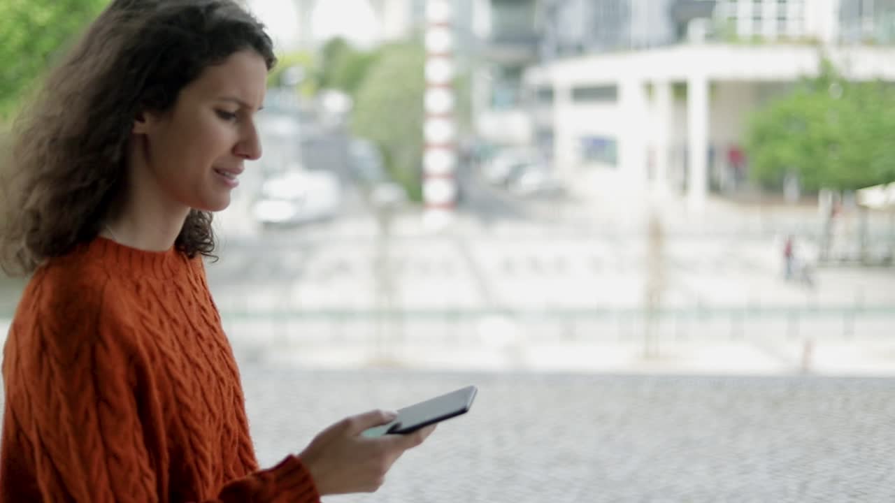 mujer joven sonriente usando un teléfono inteligente al aire libre