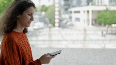 Smiling-young-woman-using-smartphone-outdoor