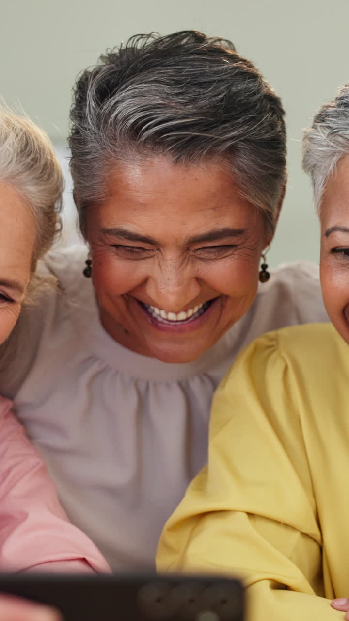 Trois femmes d’âge mûr partagent un moment de rire en utilisant un téléphone
