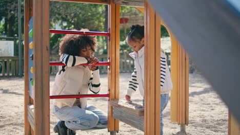 happy mother daughter playing on playground. woman looking girl