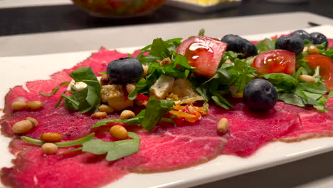 Statische-Nahaufnahme-Eines-Köstlichen-Abendessens-Mit-Frischem-Rohem-Rindfleisch-Mit-Salat,-Tomaten,-Blaubeeren-Und-Pinienkernen