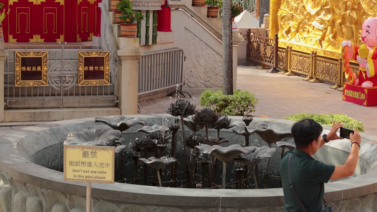 한 남자가 폰으로 분수를 잡습니다.