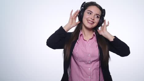 smiling happy young woman listening to music with earphones and dancing isolated on white background