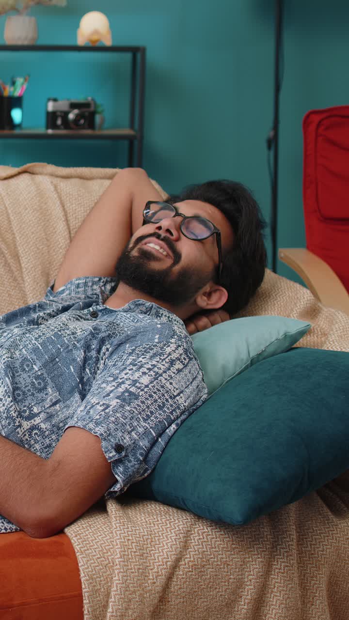 Uomo indiano stanco sdraiato a letto che si riposa a casa che fa un pisolino che si addormenta sul divano che si rilassa
