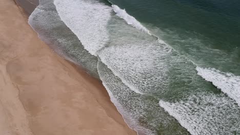 dron toma panorámica aérea olas ásperas rompiendo a lo largo de la costa en la playa de cape cod