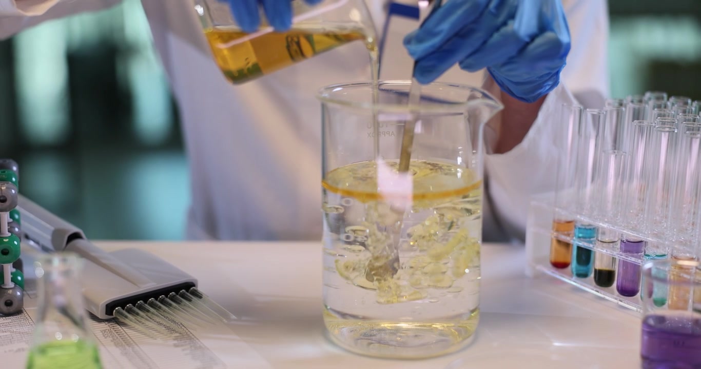 Química mistura óleo e água em béquer grande em laboratório de pesquisa.