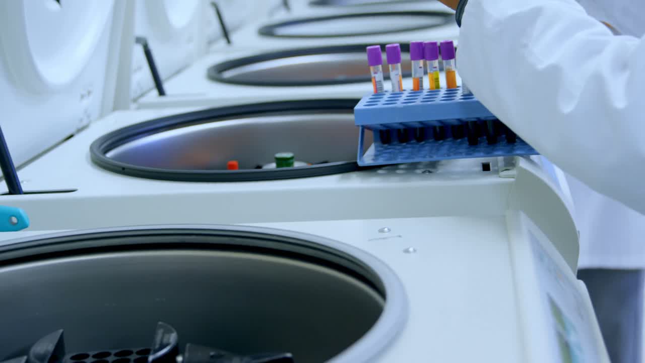 Laboratory technician placing blood samples in centrifuge 4k