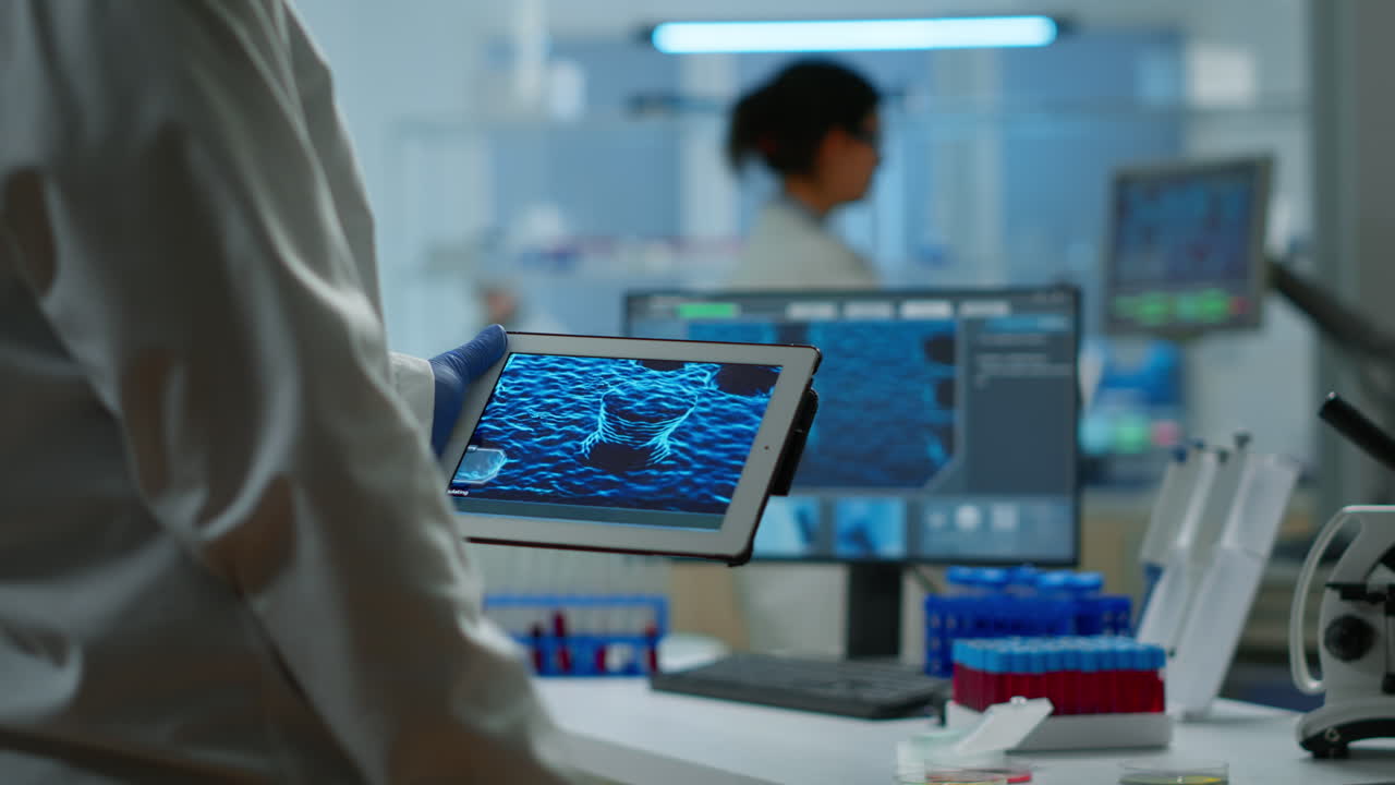 primer plano de un científico en bata de laboratorio trabajando sosteniendo una tableta