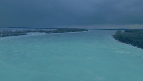 drone flies over a wide frozen river, beautiful patterns on the ice. winter landscape, blue sky over a frozen river and trees. 4k, prores