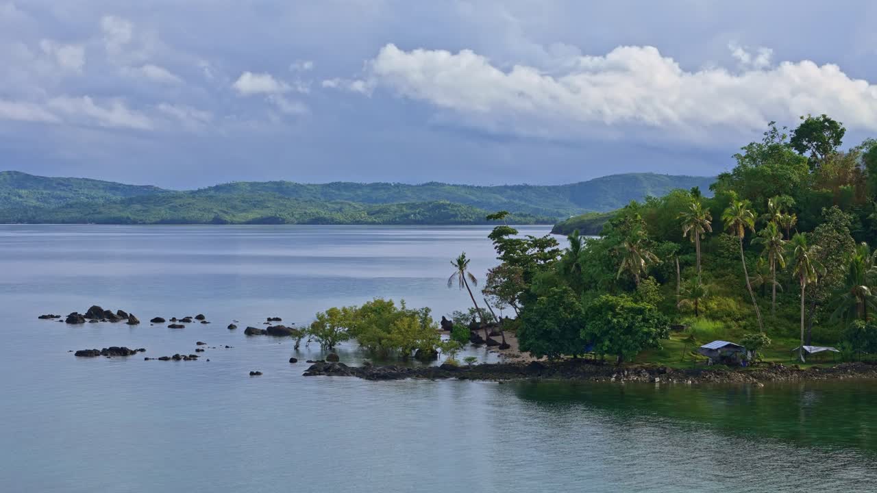 Tranquil bay view of a lush island and calm sea near Basilisa, Dinagat Islands, Philippines.