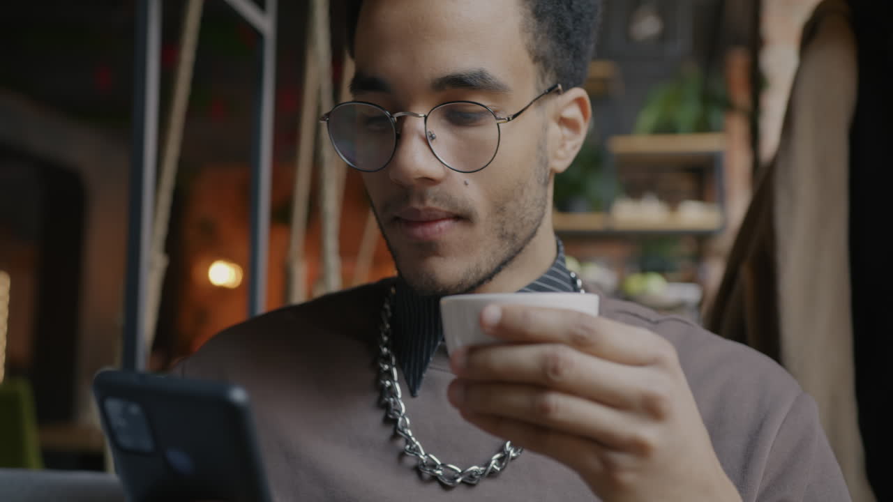Man Drinking Coffee and Using Phone in a Cafe