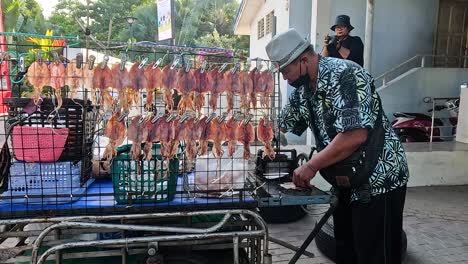 vendor prepares grilled squid at street food stall