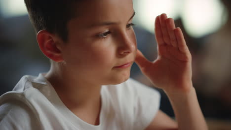 schoolboy raising hand during distance lesson. serious boy having online class