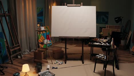 a workspace, a studio of a painter, an artist with a large easel with a canvas in the middle of the room. around the canvas scattered paints, brushes, cardboard boxes, a mess