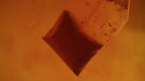 primer plano de la bolsa de té difundida en un vaso transparente. macro cámara lenta del proceso de elaboración de hierbas.