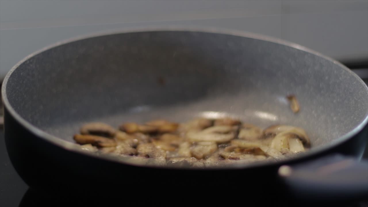 Aggiunta di pepe su funghi che bollono in padella
