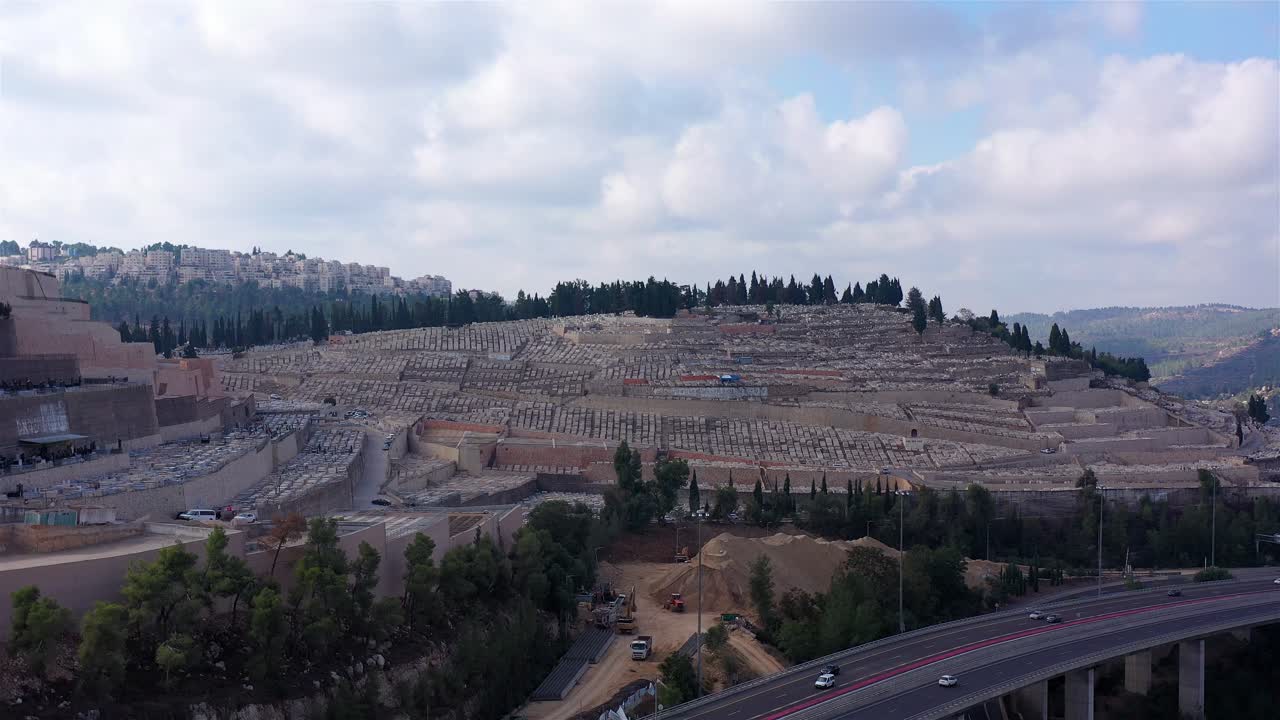 Aerial view of a vast cemetery on a hillside overlooking a highway
