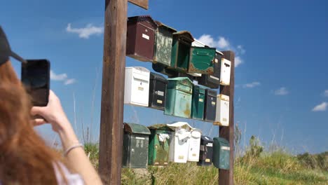 a woman photographs old mailboxes on a wooden wall in the middle of nature in mallorca