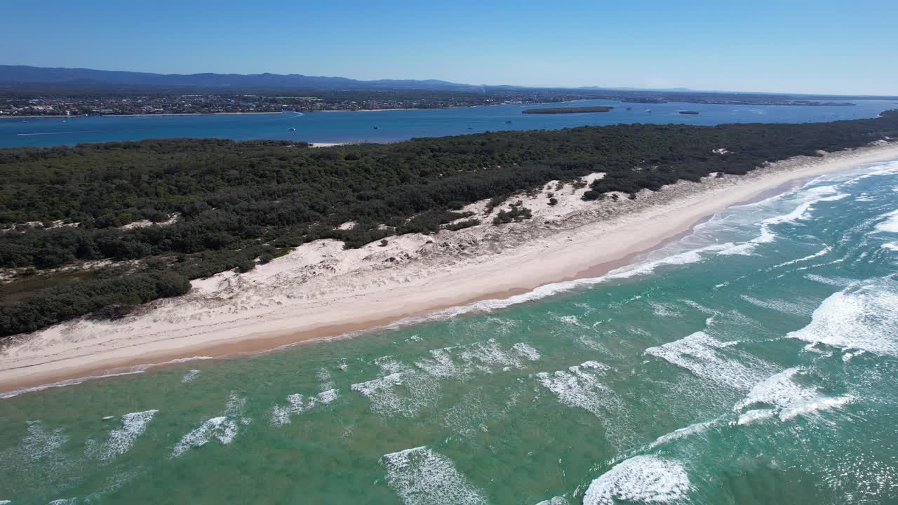 Bølger der kommer ind til den sandede kystlinje på stranden på South Stradbroke Island i QLD, Australien.