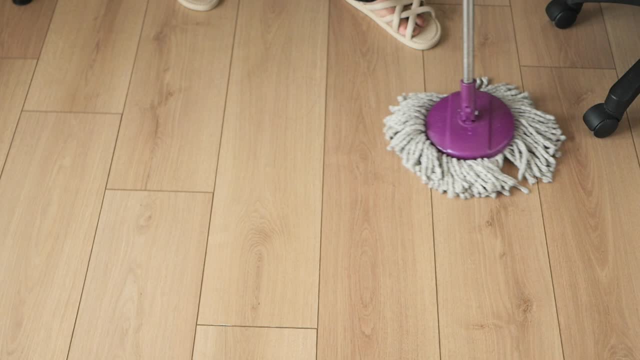 Cleaning the wooden floor with a mop