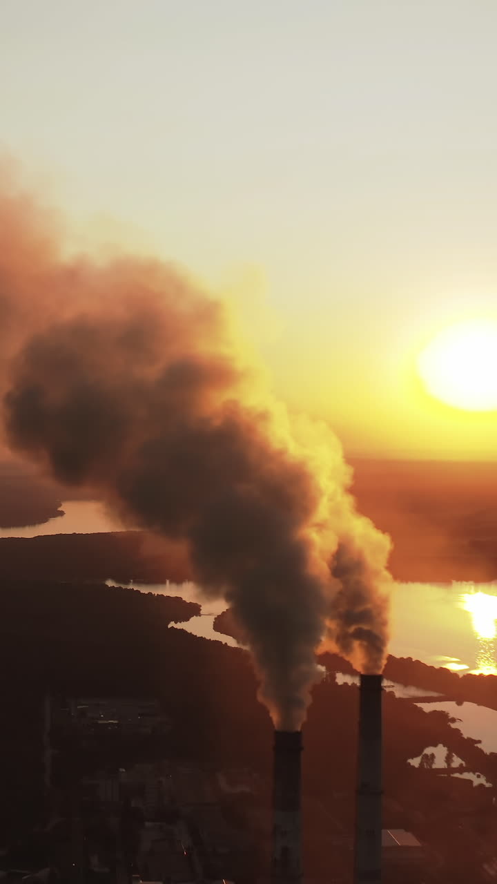 Large plant with smoking pipes. Dark smoke comes out in clouds from chimney of factory plant