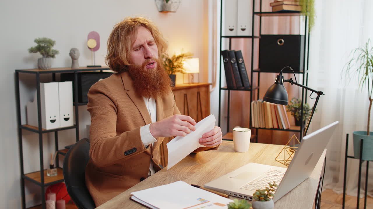 Business man opening envelope reading bad news in letter feels upset bank debt sitting at office