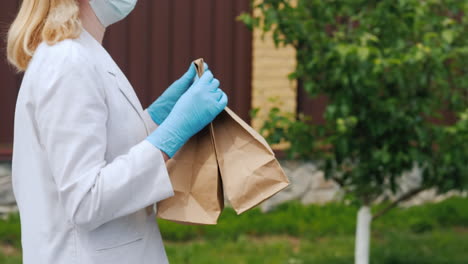 Vista-Lateral-De-Una-Mujer-Con-Una-Máscara-Y-Guantes-Llevando-Bolsas-De-Comida-A-Su-Casa