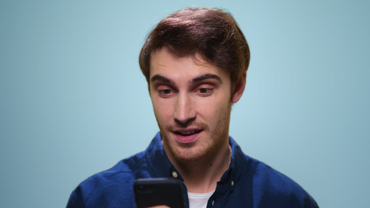 Man using smartphone on blue background. Guy browsing internet on mobile phone