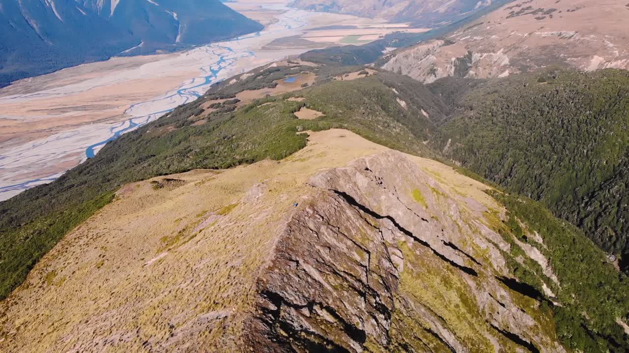 Wide river valley surrounded high mountains aerial pull back shot. Arthurs Pass, New Zealand