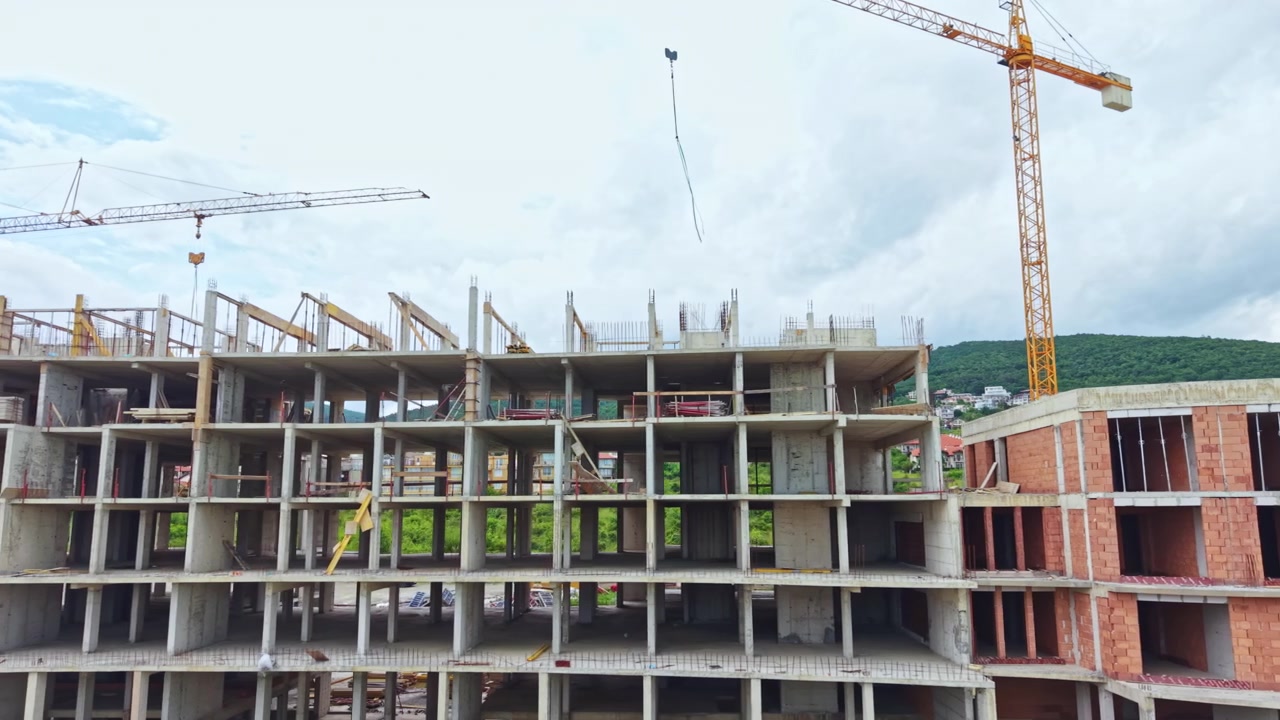 Cantiere attivo che coinvolge strutture alte e attrezzature di sollevamento. Attività di costruzione continua con gru che assistono nell'erigere strutture imponenti e impalcature