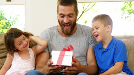 children offering a gift to their father