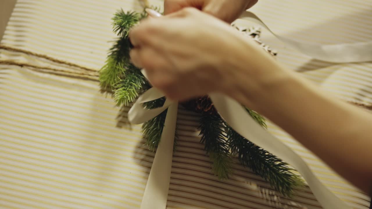 Una persona incarta un regalo di Natale con un nastro bianco. Primo piano.