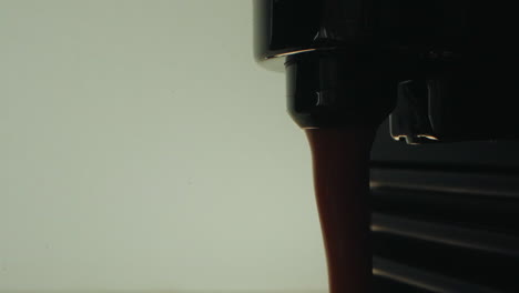 dark coffee dripping from an espresso machine with a clean white background