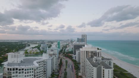 landing footage of modern urban borough at sea coast at dusk. row of luxurious multistorey apartment buildings along wide road. miami, usa