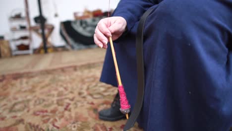 a lady hand spinning yarn in a traditional manner