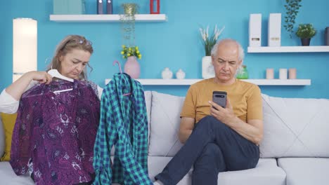 the woman tries on clothes at home and her husband helps her.