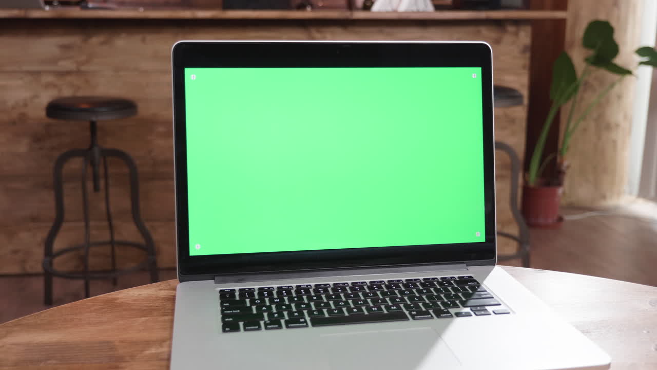 portátil con pantalla verde en la mesa de madera