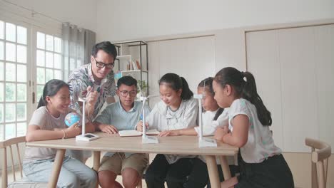 middle school classroom: enthusiastic teacher explains to a young children how wind turbines work. kids learning about eco-friendly forms of renewable energy