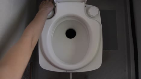 woman flushing empty motorhome removable toilet by pressing the button and creating pressure for water to flush the toilet