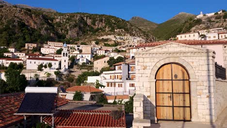 touristic village of dhermi in albanian coastline of ionian sea, stone houses with red roofs on rocky hills at morning sunshine