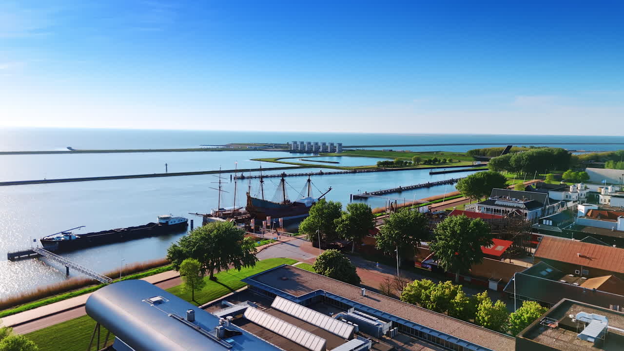 Approaching the old ship reconstruction Batavia standing at the berth. Dikes and sluices on the Merkemeer Lake at backdrop.