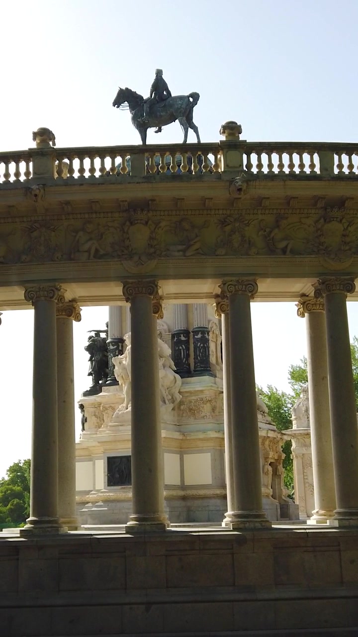 Monumento ornato con statua equestre incorniciato da colonne in un soleggiato parco cittadino