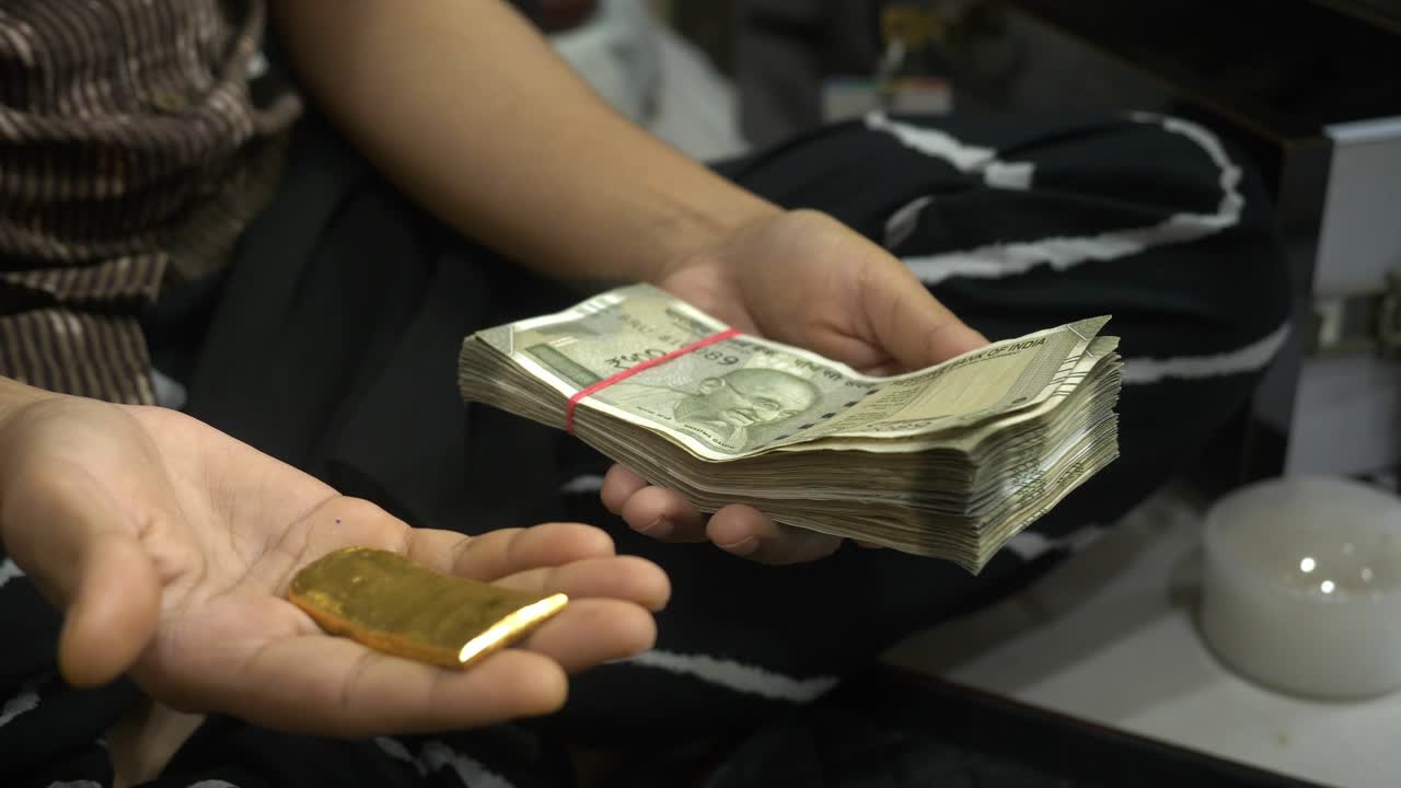 Hands comparing 24k raw gold and Indian rupee banknotes for gold investment, Closeup