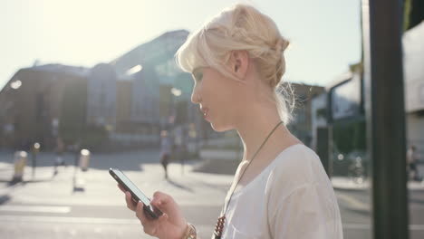 piękna blondynka używająca smartfona w mieście.