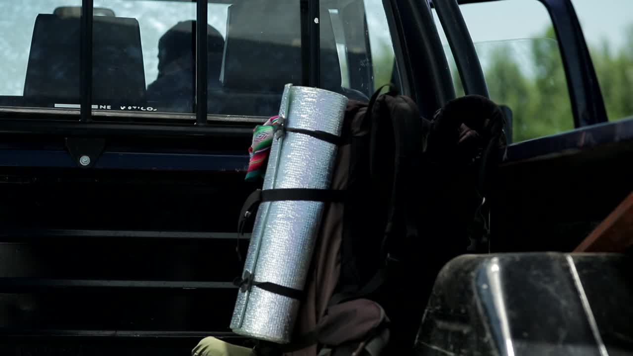 Traveler throwing backpack on load area of pick up car for trip,close up