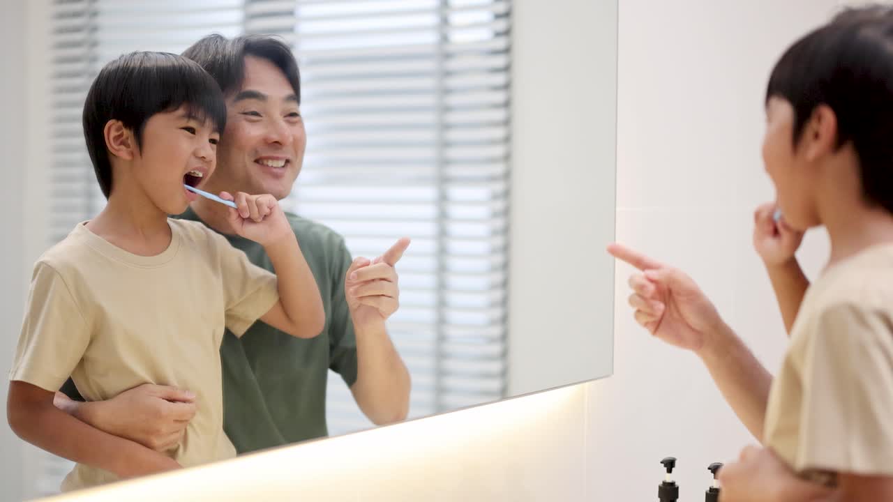 A father and son share a joyful moment brushing teeth in a brightly lit bathroom