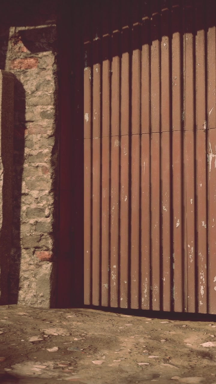 Porta di legno in un muro di pietra con la luce del sole che proietta ombre serali.