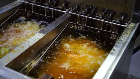 cocinero poniendo pollo en aceite de freír en un restaurante comercial