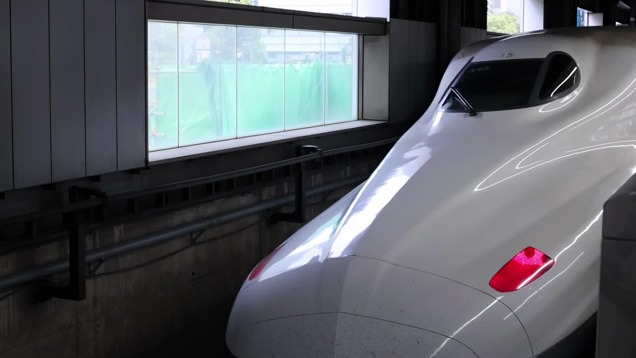 Close-up of a high-speed train's aerodynamic nose inside a station tunnel.